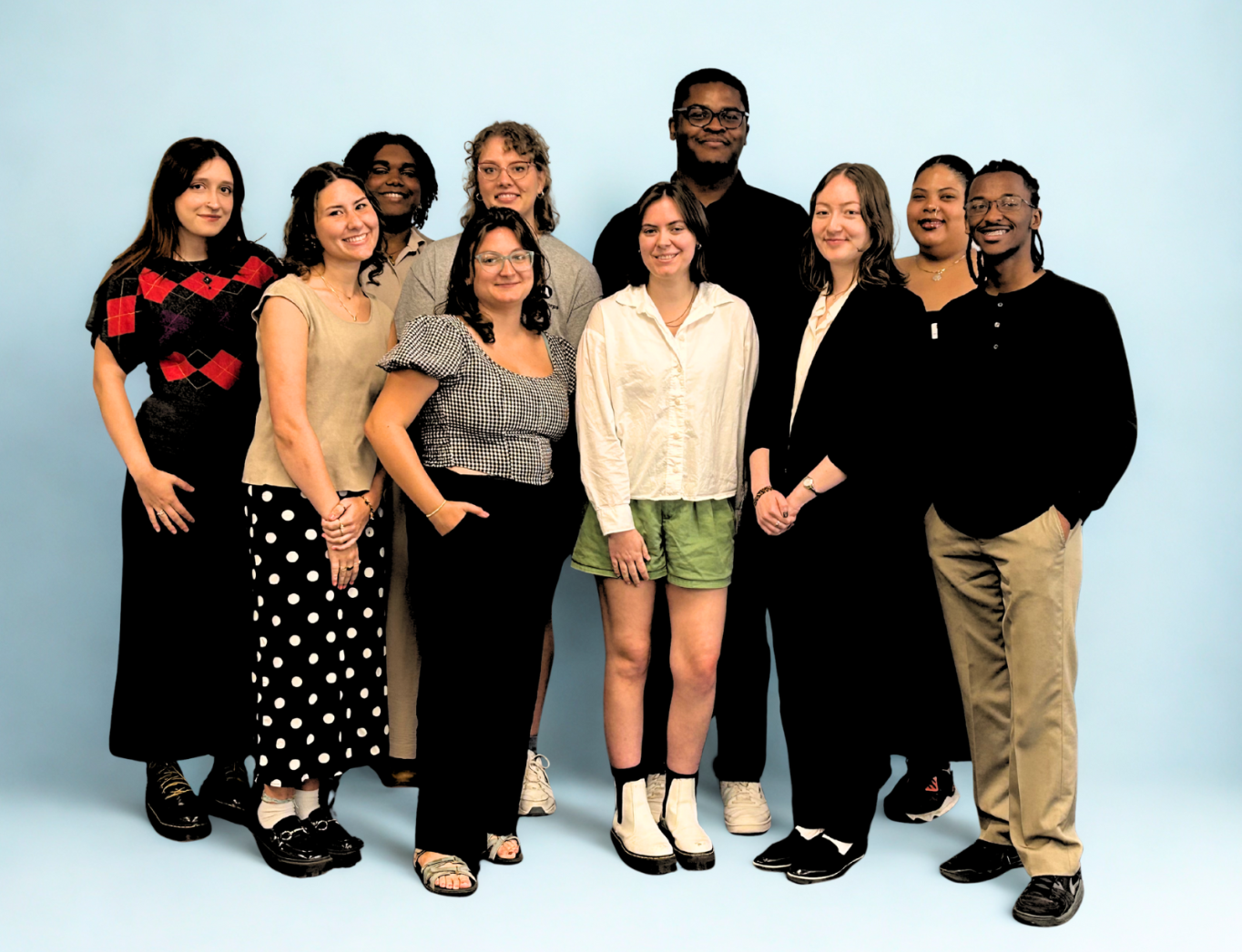 A group of people pose for a photo in front of a light blue background