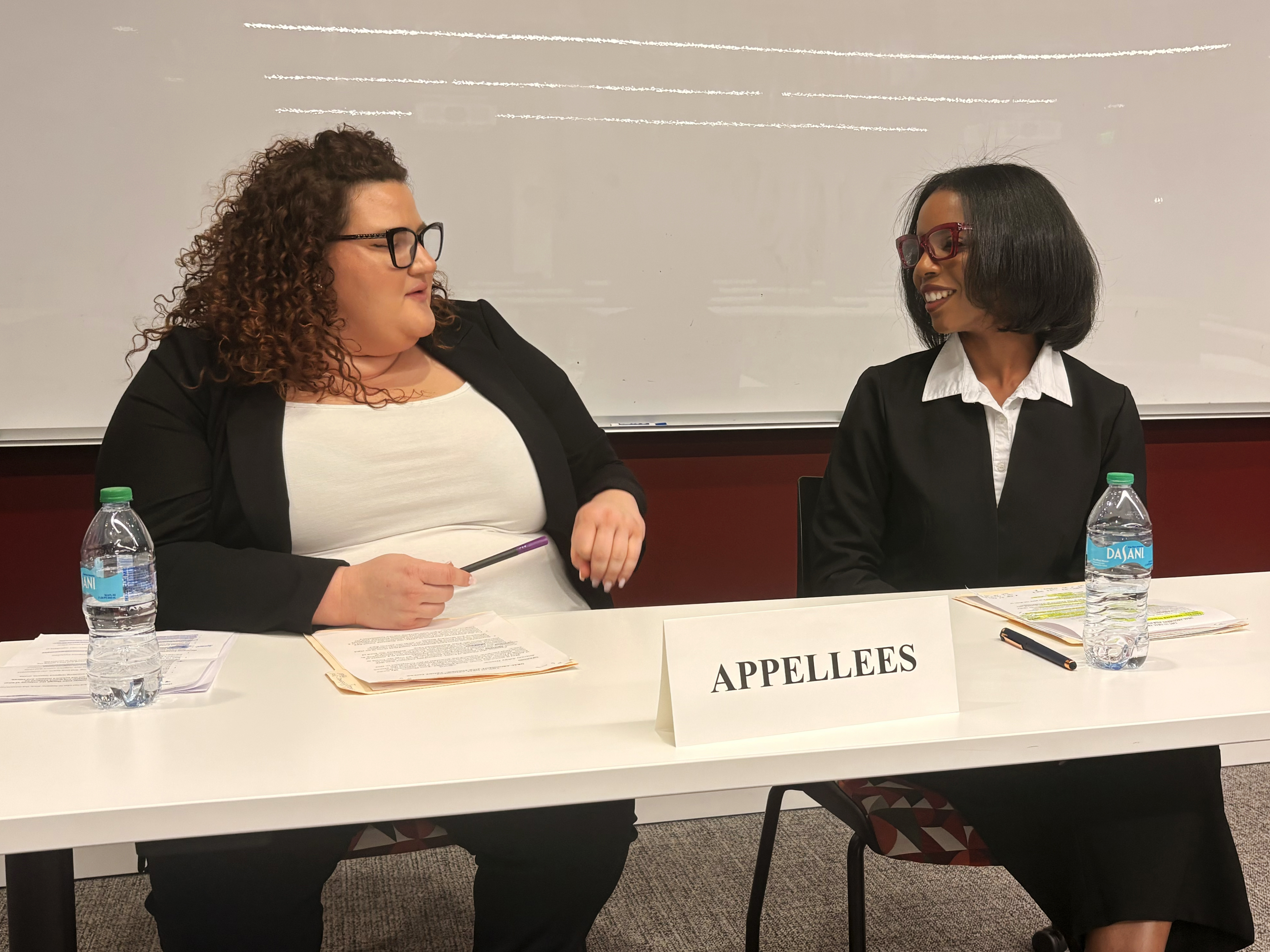 two students seated at a table. A placquard withthe word "Appellant" is on the table.