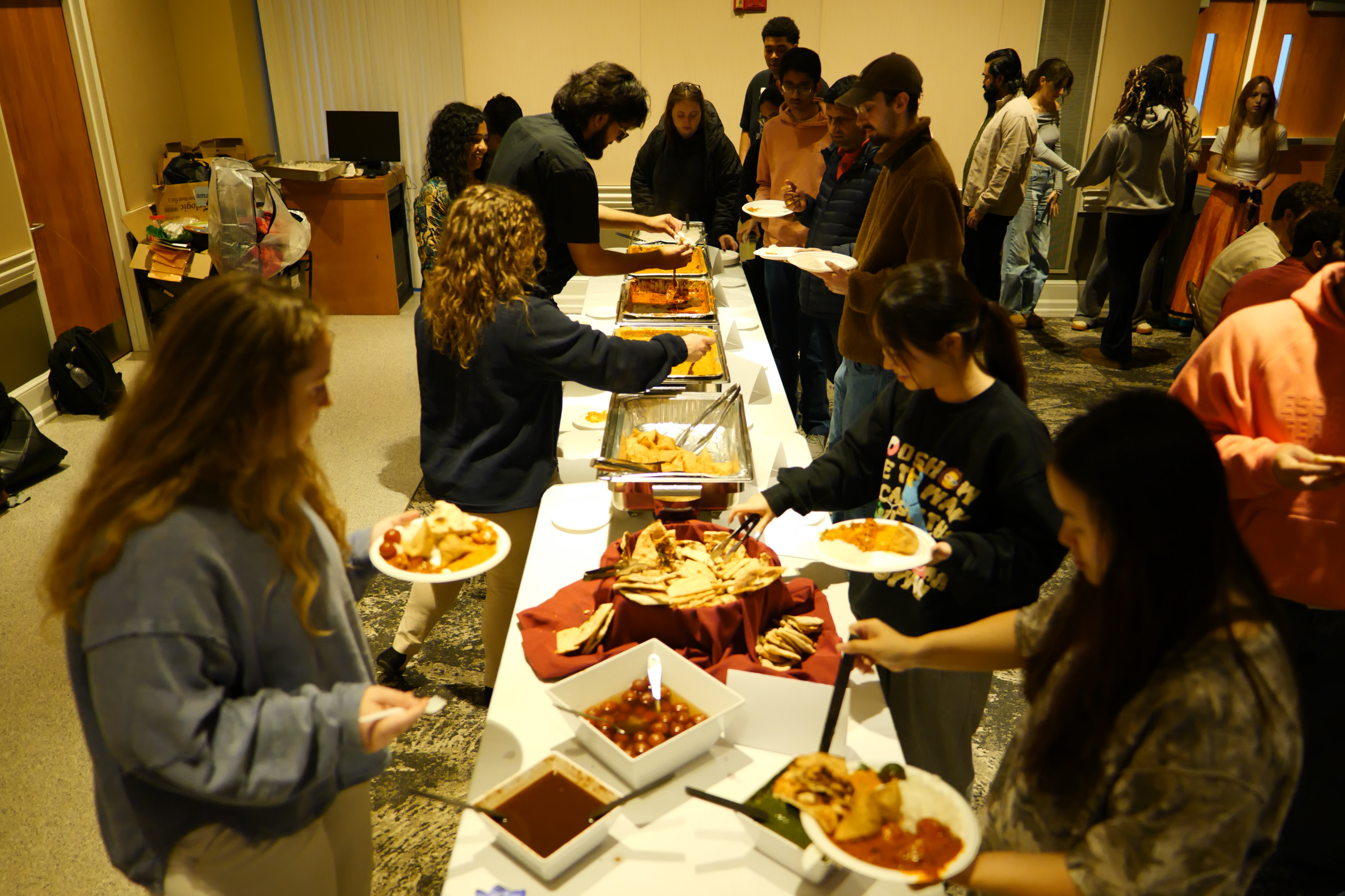 A group of people take food from a buffet