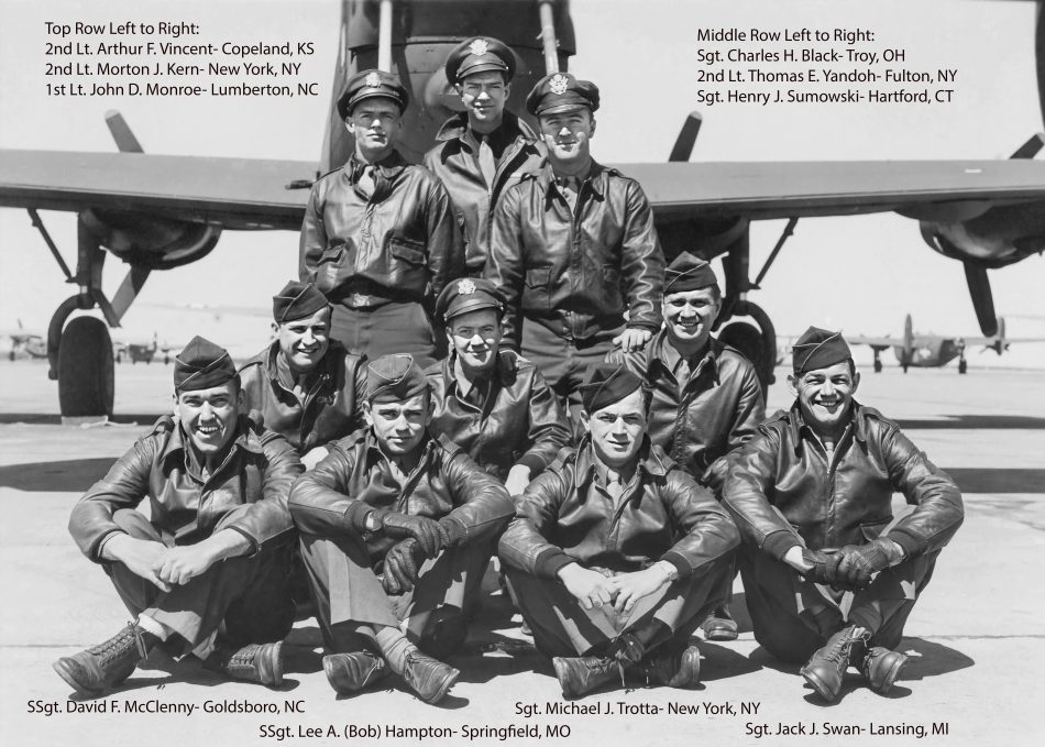 Black and white photo of 10 servicemen in dress uniforms in front of an airplane