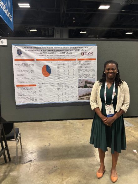 Woman stands next to a poster presentation at a conference