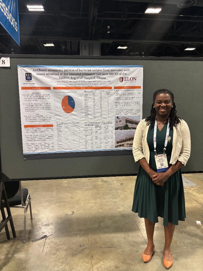 Woman stands next to a poster presentation at a conference