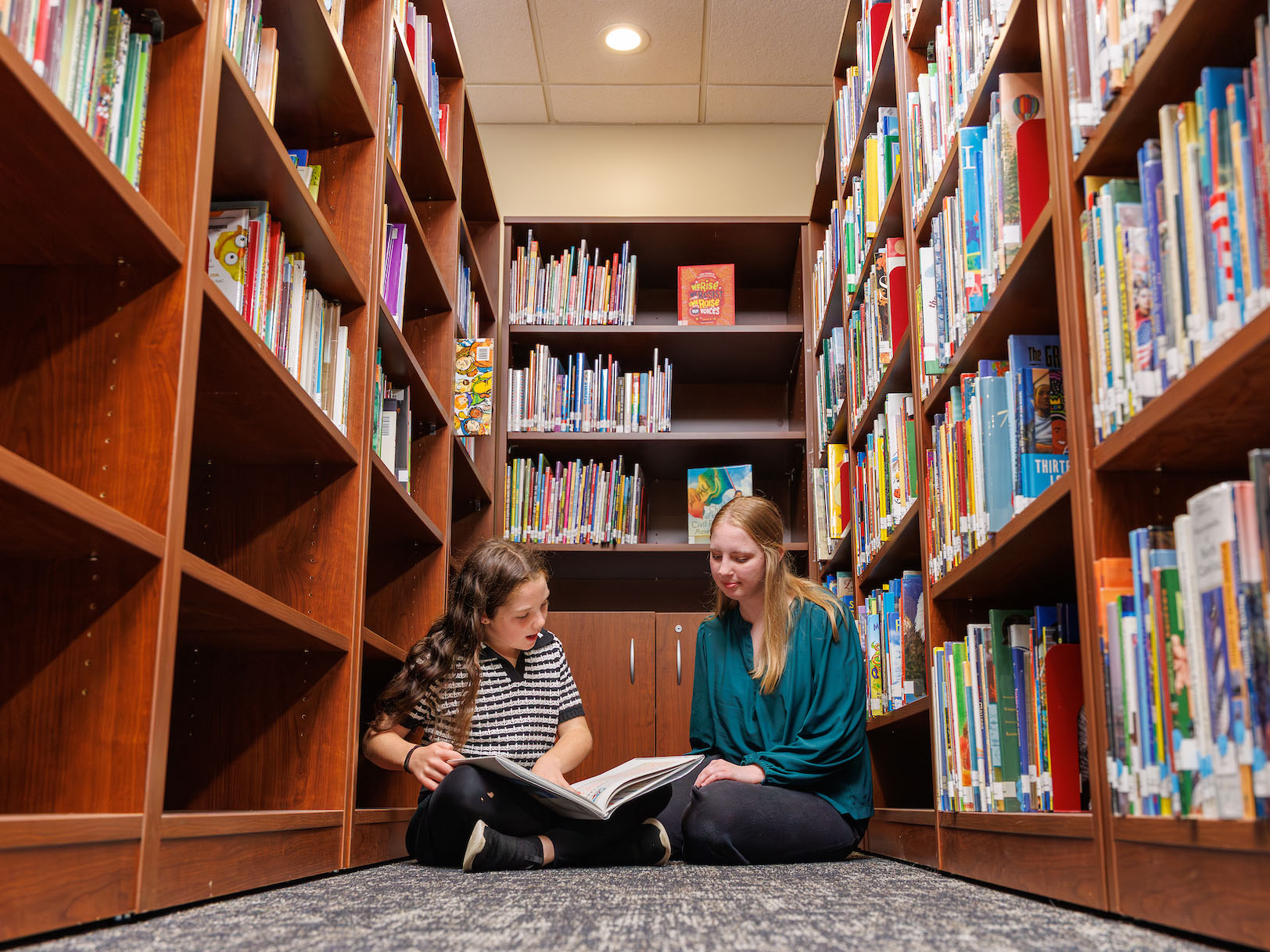 Photo of a child and a college student reading a book together on the campus of Elon University in North Carolina.