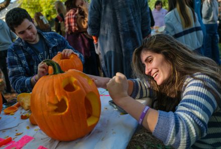 Two people carve pumpkins on a table