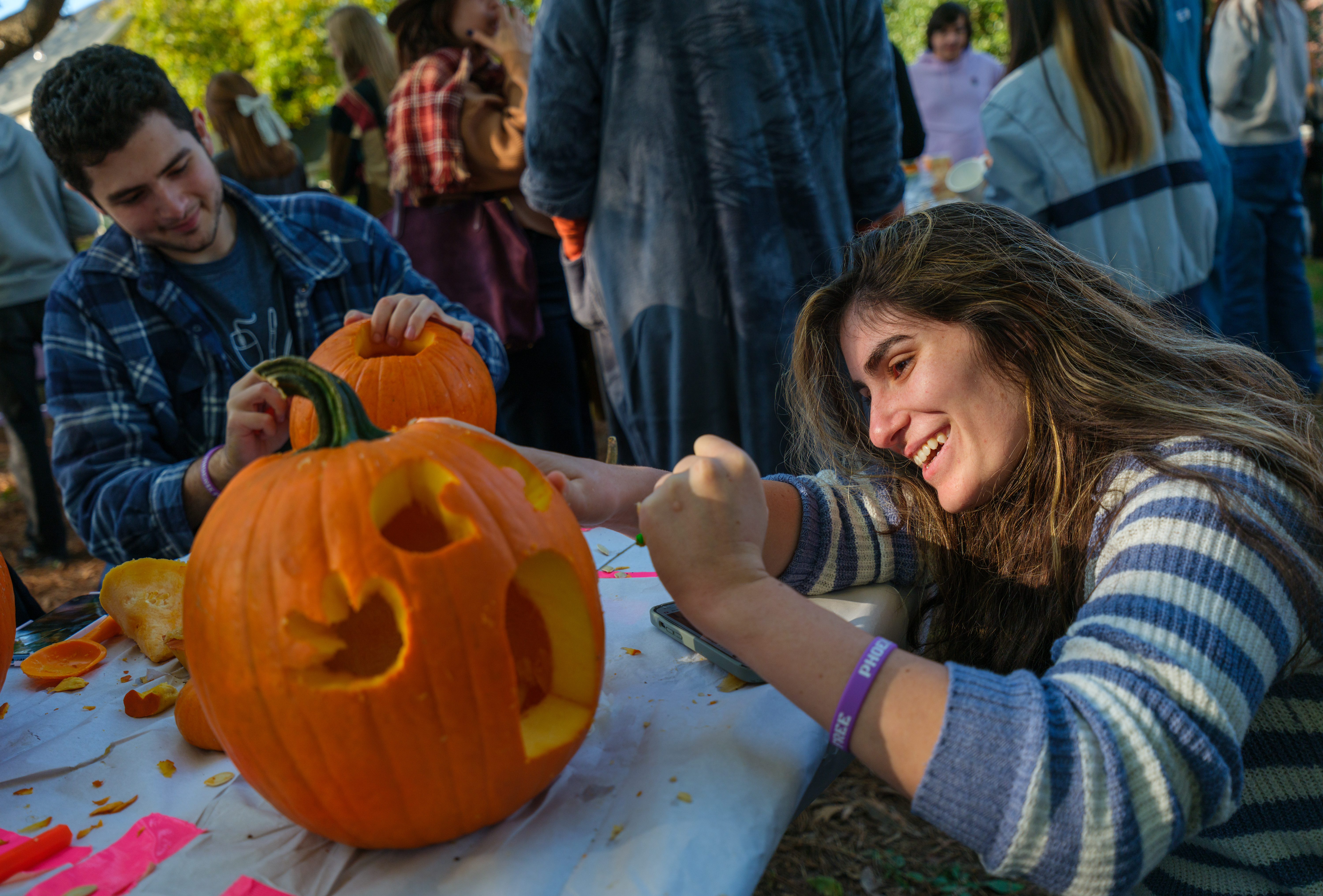 Two people carve pumpkins on a table