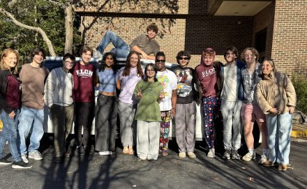 A group of people pose in front of a tan brick buidling