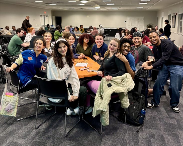 A group of people sit at a table together and smile toward the camera