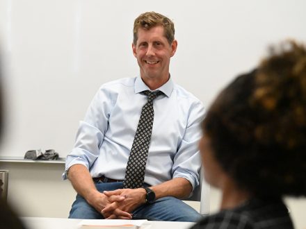 Phillip Motley sits in front of an Elon classroom.