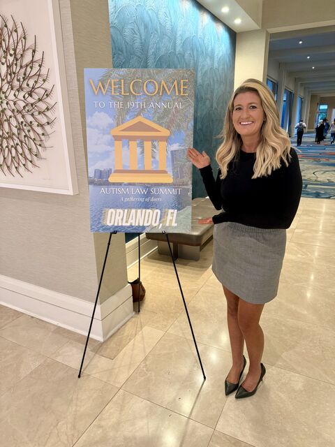 A woman stands next to a poster board that says 