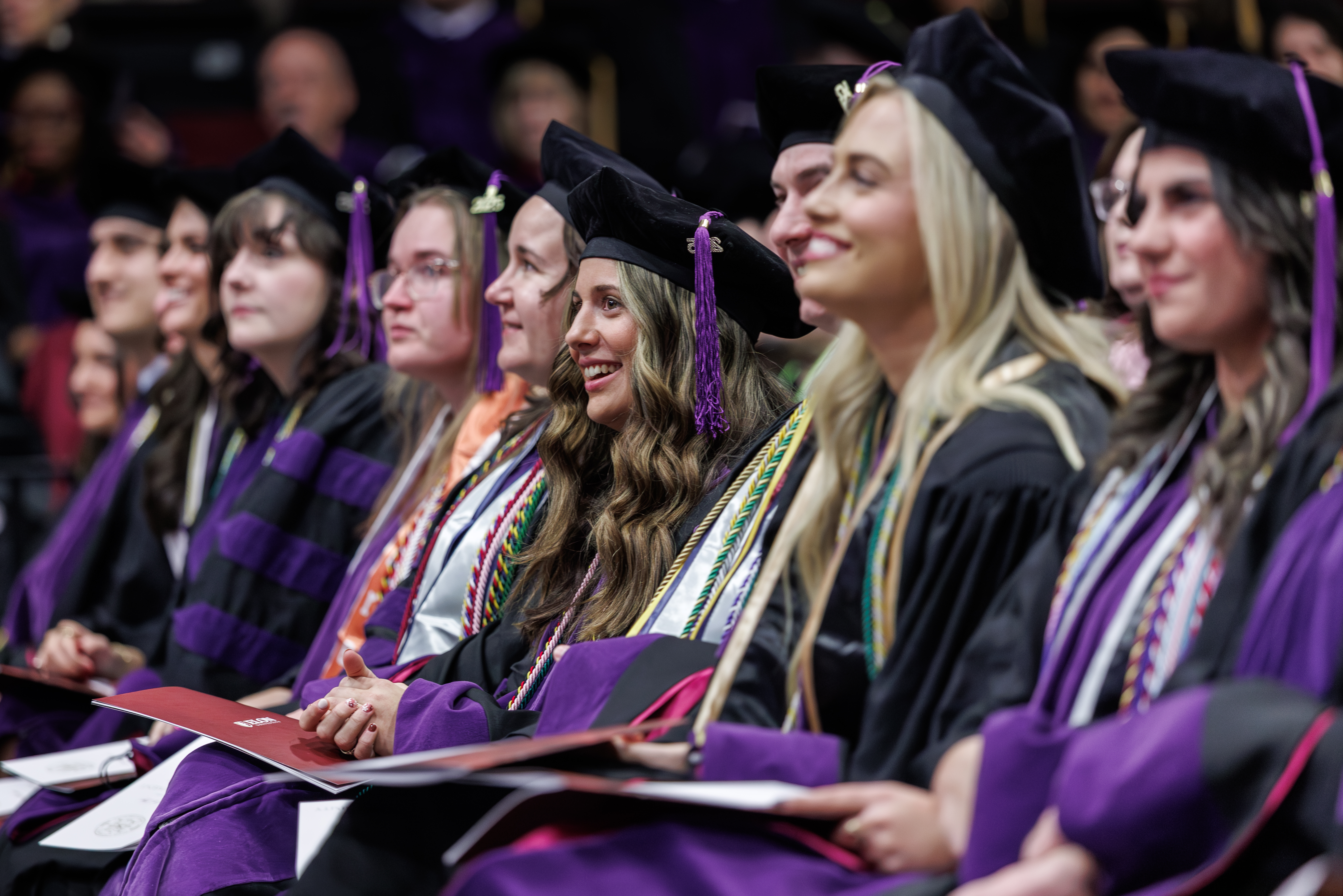 A group of Elon Law graduates seated in an auditorium, smiling.