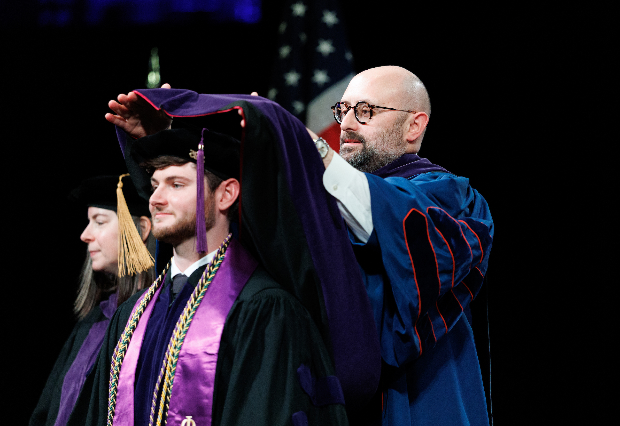 A male student being hooded by Dean Zak Kramer