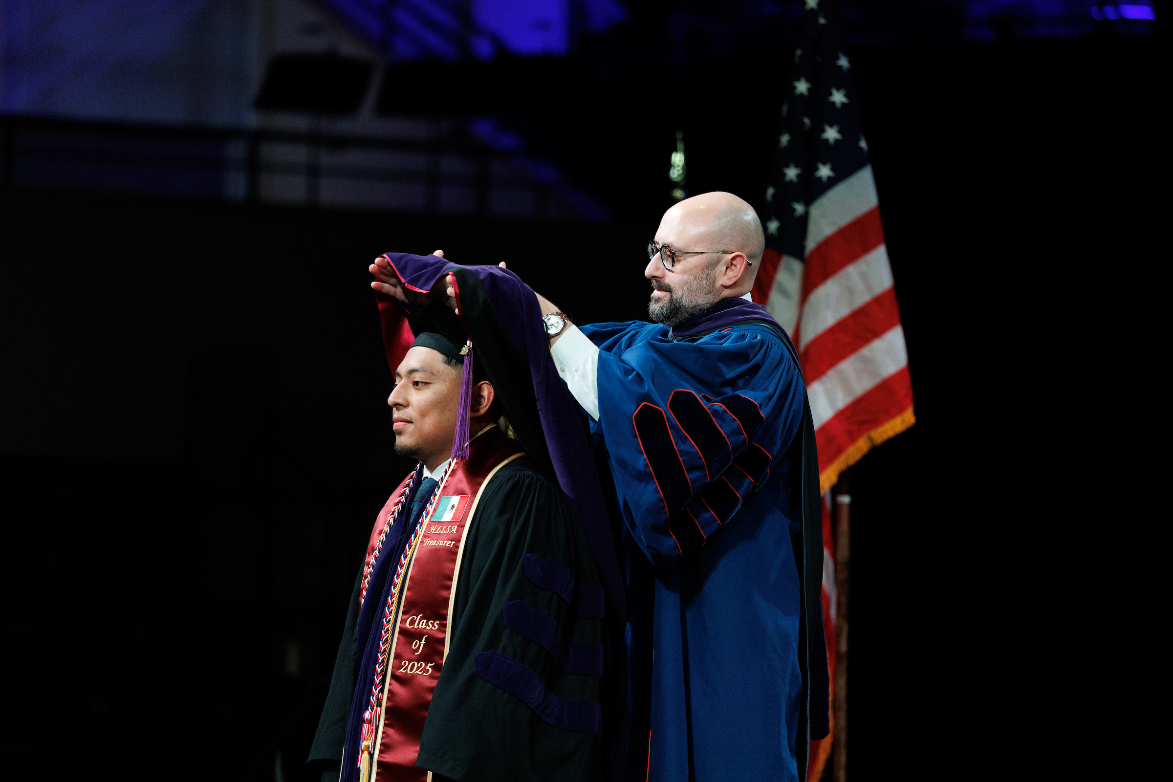 A male student being hooded by Dean Zak Kramer