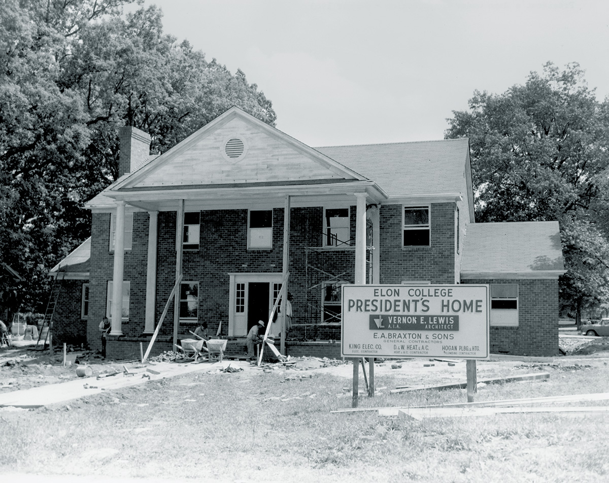 A black-and-white photograph shows the construction of the Elon College president’s home, with workers and scaffolding visible.