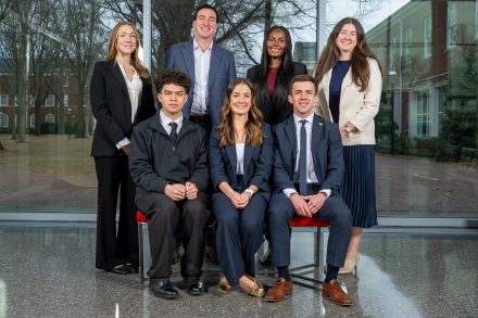 Seven people pose for a photograph in business attire