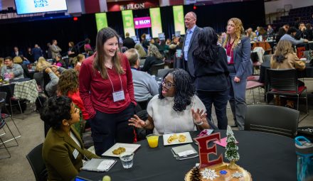 Attendees talk and laugh around a table during Elon University’s Winter Symposium.