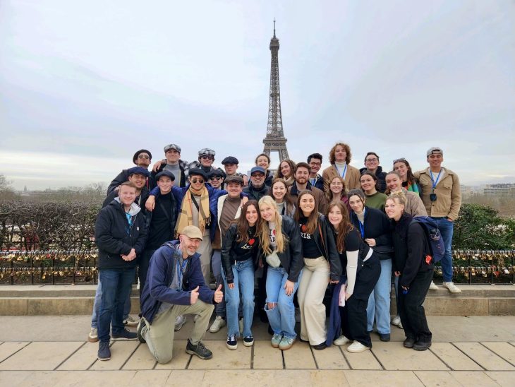 A group of people pose in front of the Eiffel Tower in Paris, France