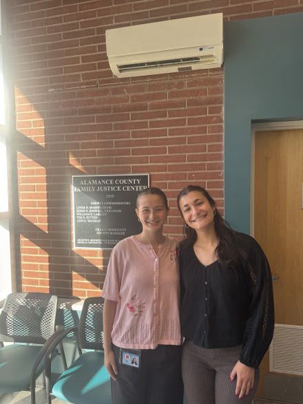 Two female students posing together at their internship at the Family Justice Center of Alamance County.