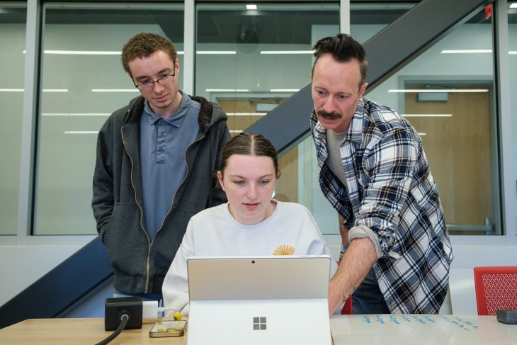 Associate Professor of Astrophysics Chris Richardson, Jaylem Cheek and and Cayden Tirak looking at a computer.