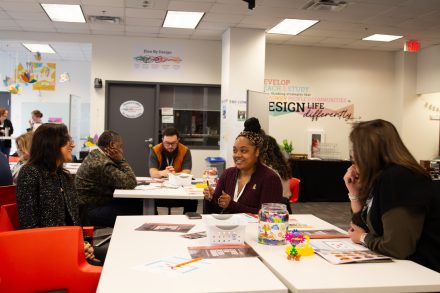 Three women sitting at a table discussing design ideas.