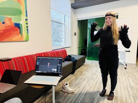 Female student with blonde hair wearing all black is recording Mocap animations for their game. 
