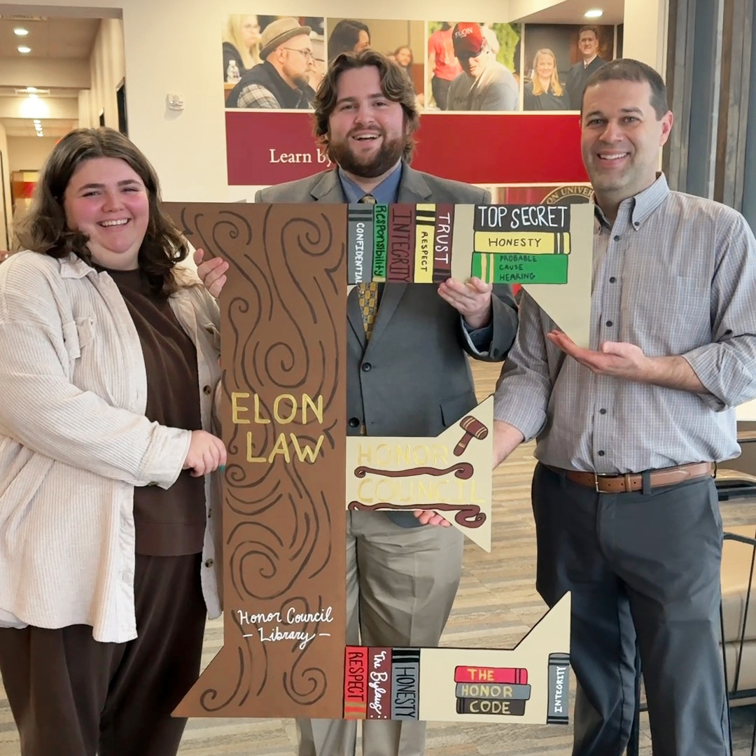 Three law students with a large decoratively painted E.