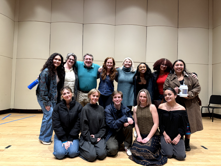 A group of people pose in a space with padded walls and a wood floor