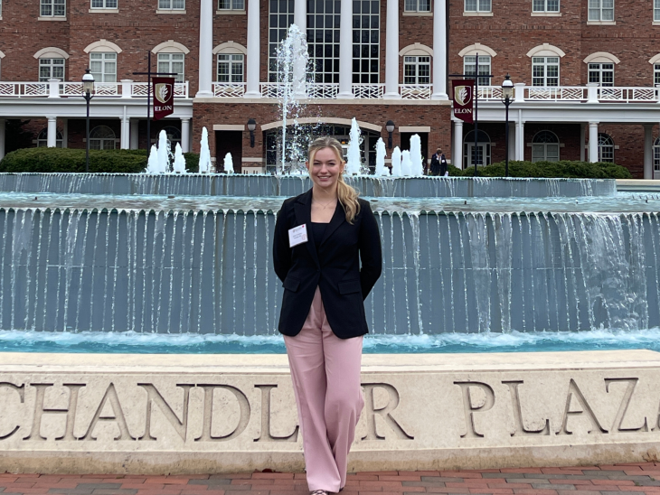 Izzie Crowley '28 posed in front of Ernest A. Koury Sr. Business Center