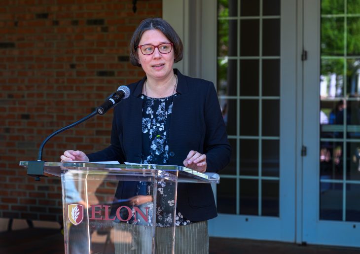 Andrea Sinn standing in front of a podium speaking at the event celebrating three decades of International & Global Studies.