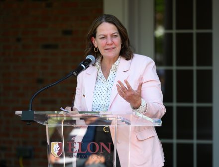 President Connie Ledoux Book wearing a pink blazer and white blouse giving remarks at the podium for the International & Global Studies 30th anniversary event.