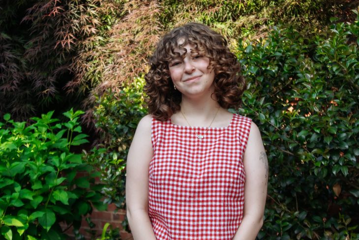 Elon student in front of spring foilage.