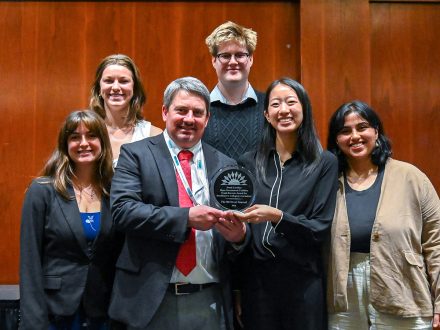 Student journalists from Duke University’s 9th Street Journal smile with a Summit plaque