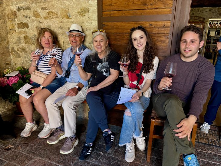 Five people sit holding glasss of wine