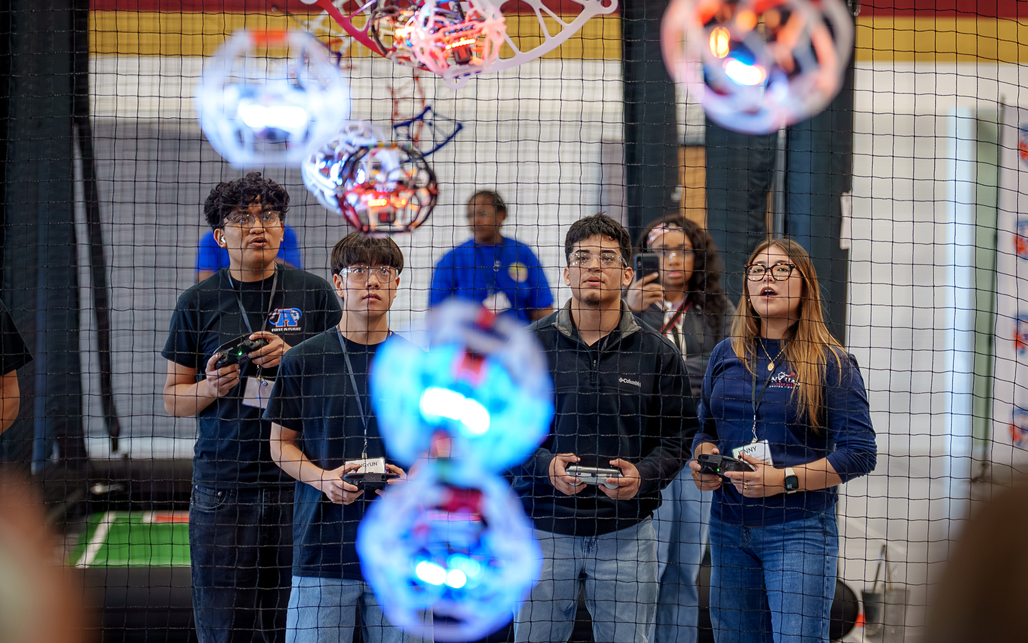 A group of students stand near a drone soccer arena net at ������Ƶ.