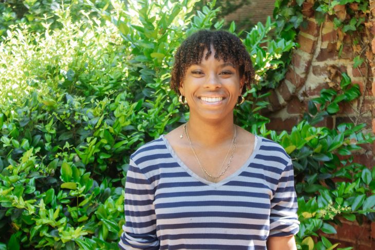 Elon student in front of spring foilage.