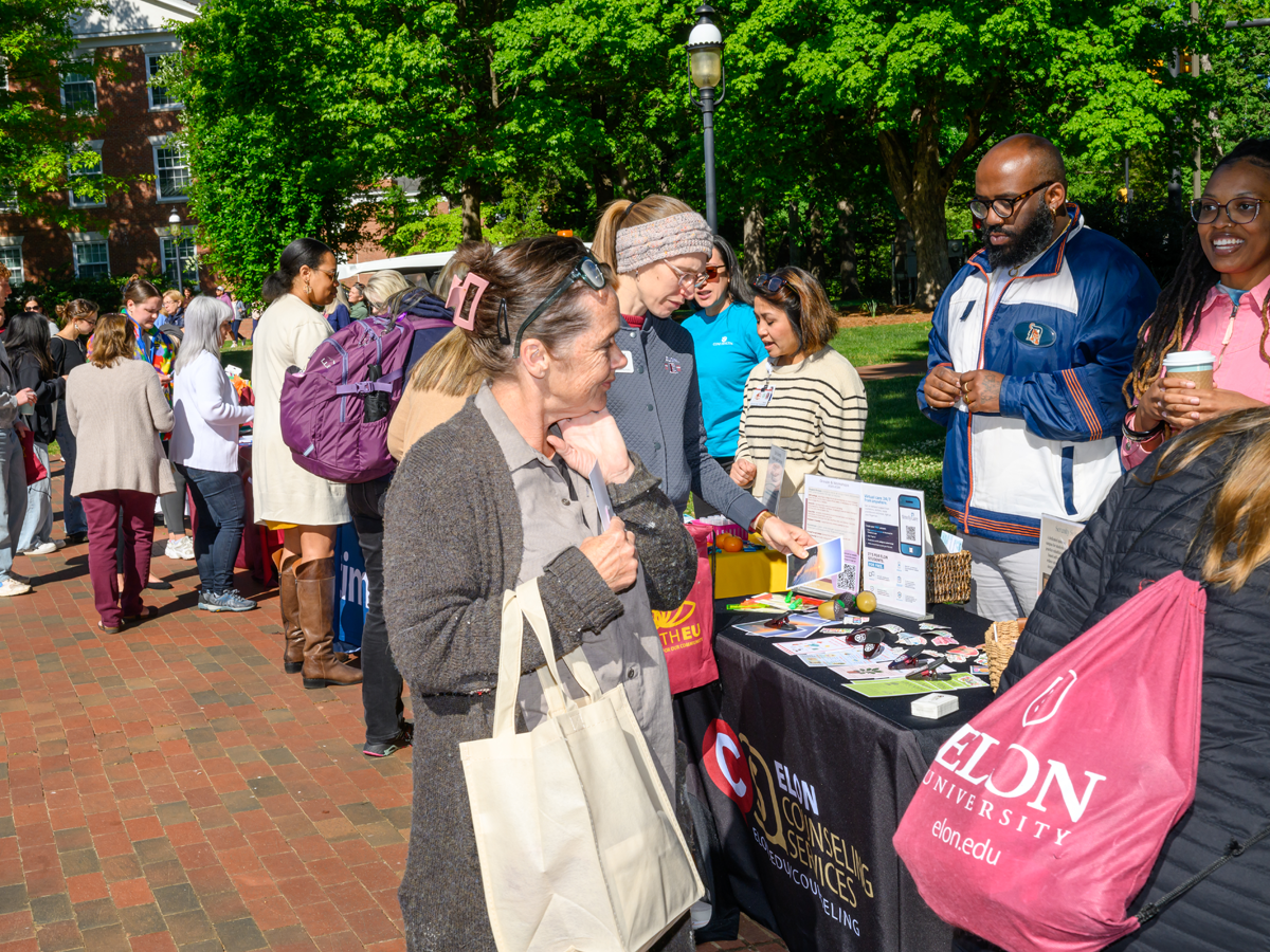 Students, faculty and staff connect with campus partners at outdoor resource tables, exploring wellness programs and gathering information during a HealthEU community event.