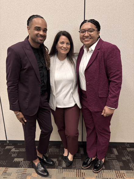 From left to right, Jonathan McElderry, Megan Noltemeyer and Destiny Payne pose together in coordinated maroon and neutral attire, smiling in a conference setting.
