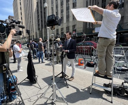 Doug Williams '13, seen here reporting live from the federal courthouse in New York, along with lots of equipment.