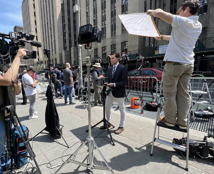 Doug Williams '13, seen here reporting live from the federal courthouse in New York, along with lots of equipment.