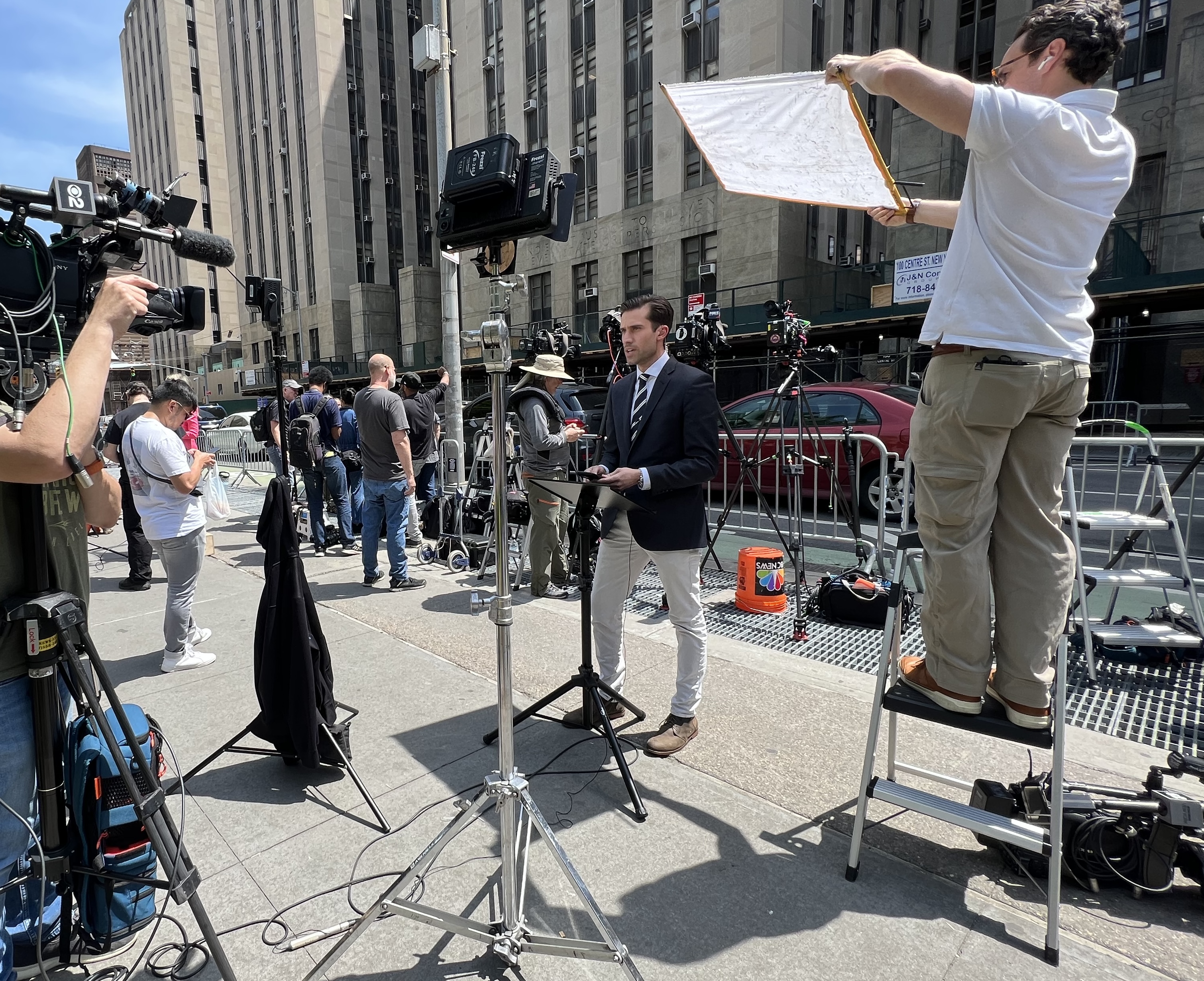 Doug Williams '13, seen here reporting live from the federal courthouse in New York, along with lots of equipment.