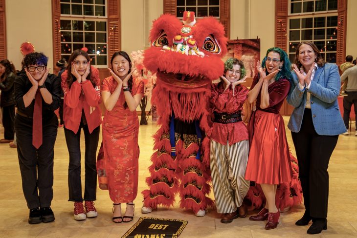 Emily Wright '28 and others who helped plan the annual Lunar New Year Celebration pose next to a red dragon.
