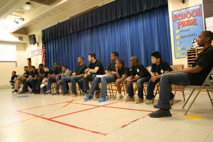 Jensen Roll '16, sits in a chair alongside other elementary school students in conversation.