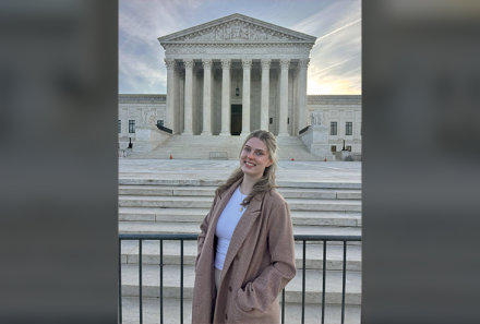 Isabel Craige at the steps of the U.S. Supreme Court at dawn. She is smiling at the camera.