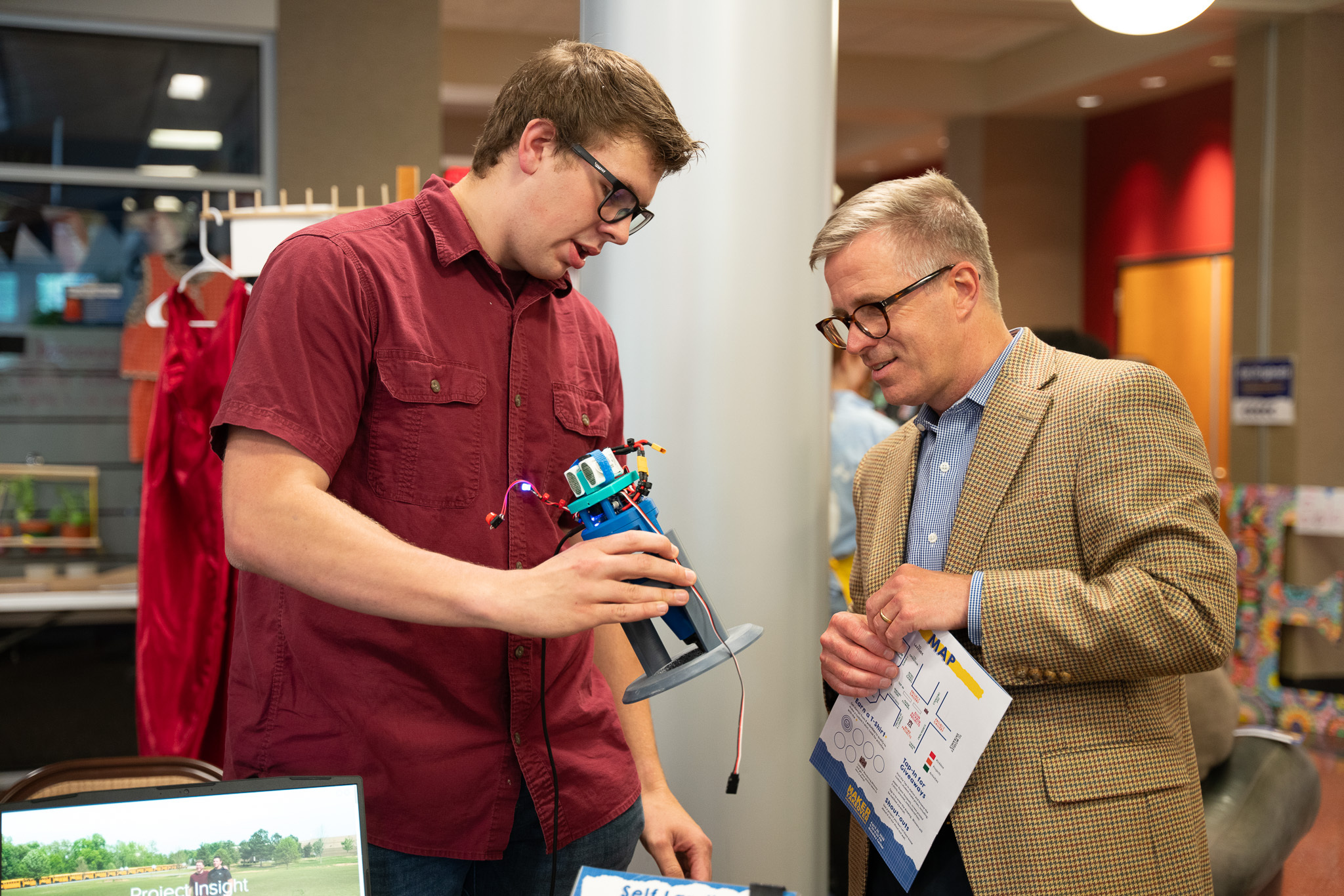 a student shows an object created through the kickbox project in the maker hub to an interested participant