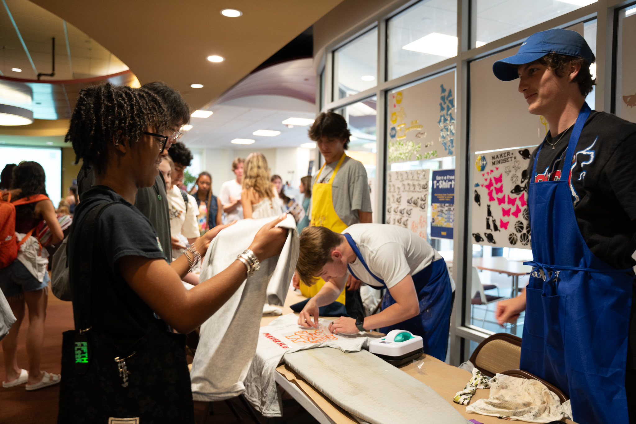 a maker takeover participant looks at a t-shirt that a maker hub employee is helping them customize