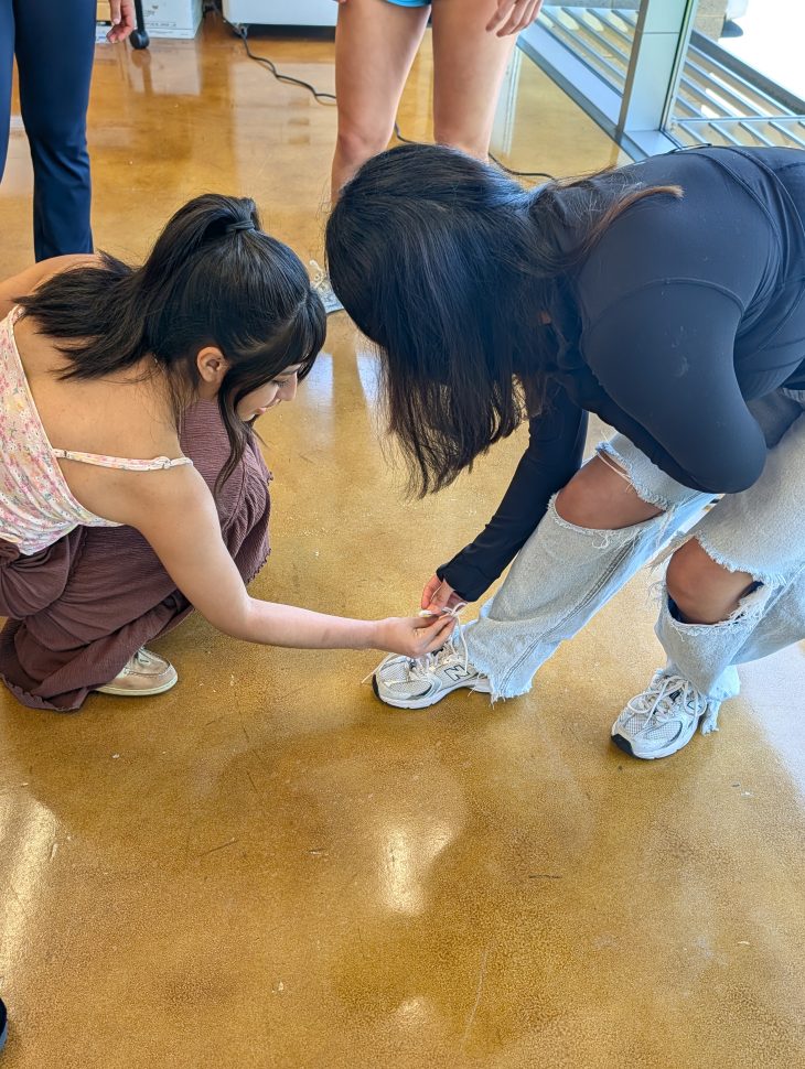 Students learning motor control associated with tying a shoe lace working in coordination with another individual