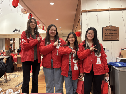 From left to right, Olivia Mohil ’27, Reagan Wible ’26, Keopagnapech Ngoun ’26 and Emma Hash ’26 pose together in coordinated red jackets during a festive indoor celebration. Smiling and standing close, the group captures a lively moment, with Ngoun and Hash—roommates—adding to the sense of connection and camaraderie.