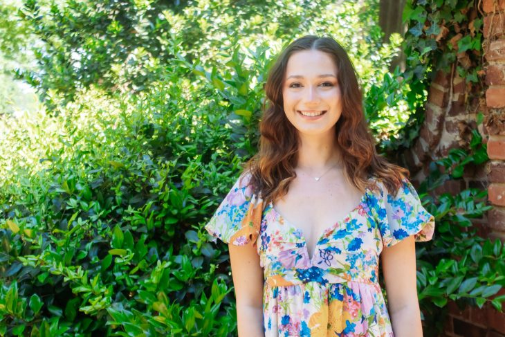 Elon student in front of spring foilage.