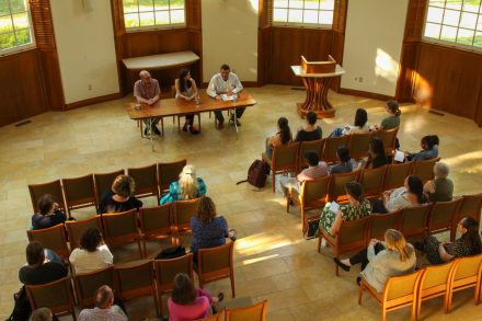 People sitting in rows looking at three high school English teachers on the panel. 