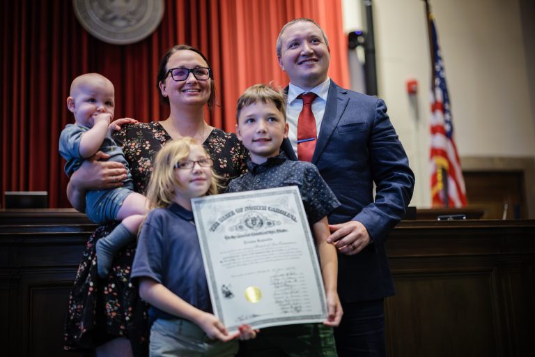 A family smiles for a photo in the front of a courtroom.
