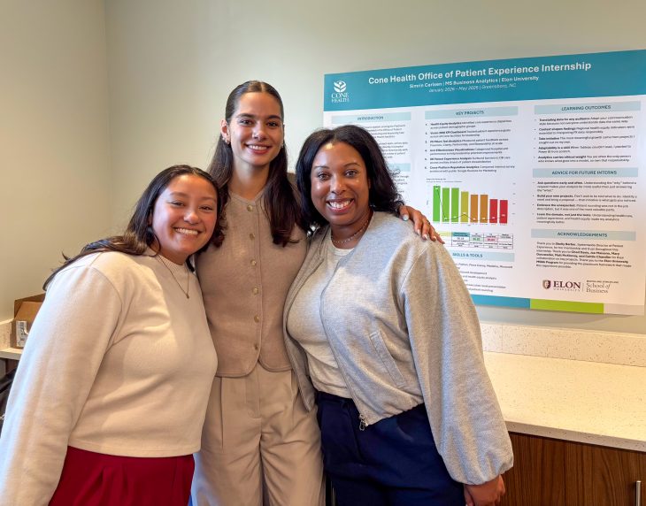 Simrin Carlsen G’26 stands with two classmates in front of her Cone Health Office of Patient Experience Internship research poster.